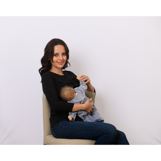 Woman breastfeeding in black nursing top with ruffle detail, front-layer design for easy nursing access, and soft breathable fabric.