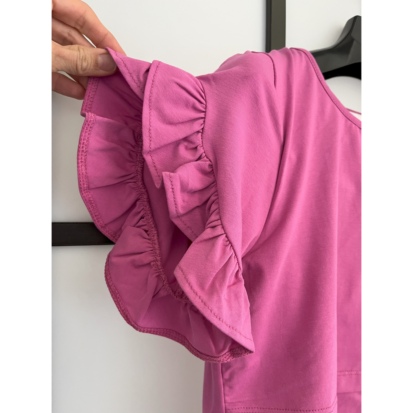 Close-up of magenta breastfeeding nursing top showing ruffle sleeve design and front-layered nursing access.